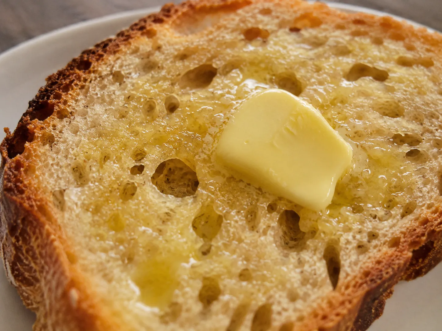 A slice of warm toasted bread with melting butter highlighting golden crust and creamy texture